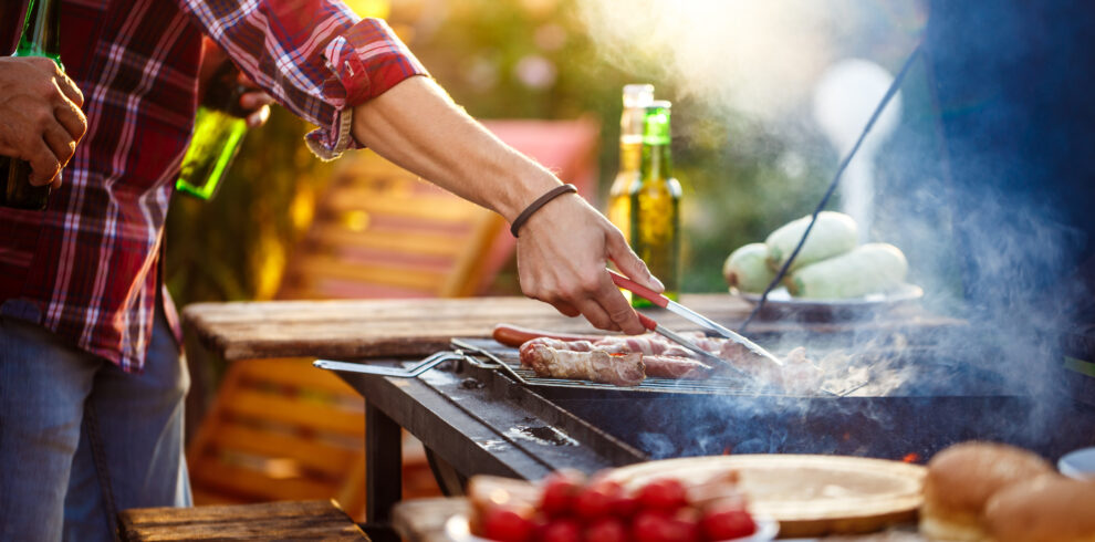 Young men roasting barbecue on grill in cottage countryside.